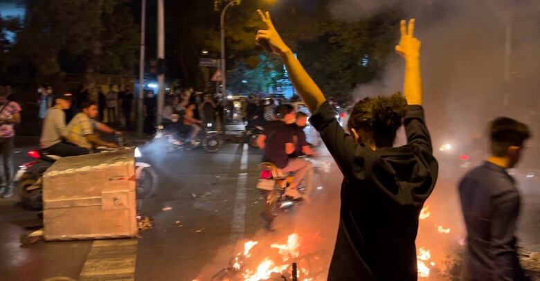 A picture obtained by AFP outside Iran shows shows a demonstrator raising his arms and makes the victory sign during a protest for Mahsa Amini, a woman who died after being arrested by the Islamic republic's 