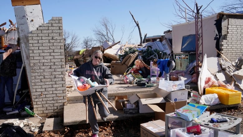 A woman removes items from a demolished house.