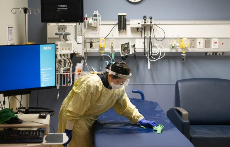 A nurse wipes down a hospital bed.