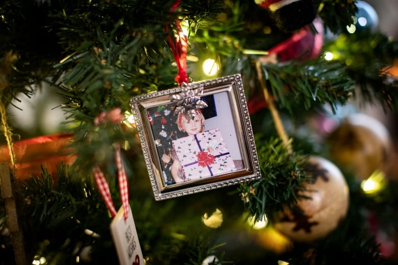 A hanging locket-style ornament with a young child holding up a gift.