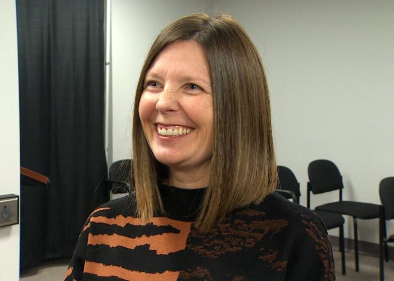 A person with shoulder length hair smiles.