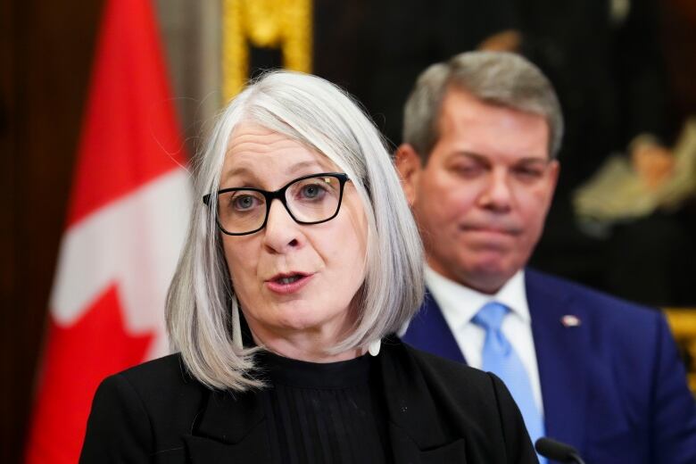 A woman with glasses speaks to media in the foyer of the House of Commons on Parliament Hill in Ottawa. 