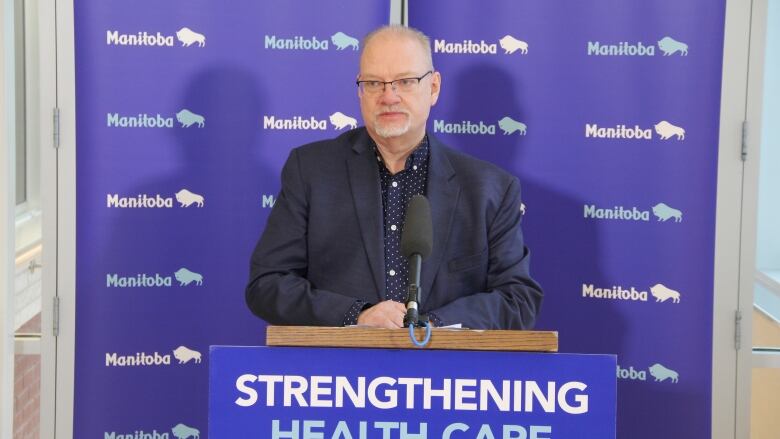 A man stands at a podium with a microphone attached. 