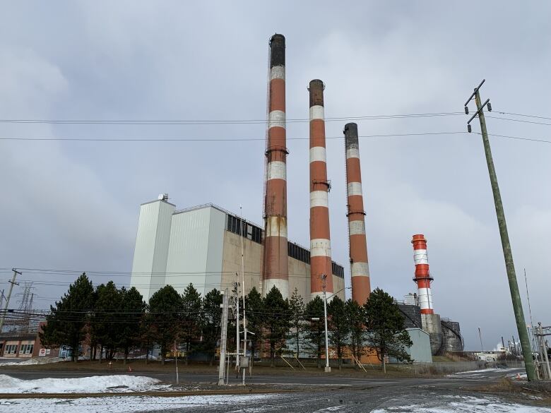 Four red and white smokestacks stand against the sky.