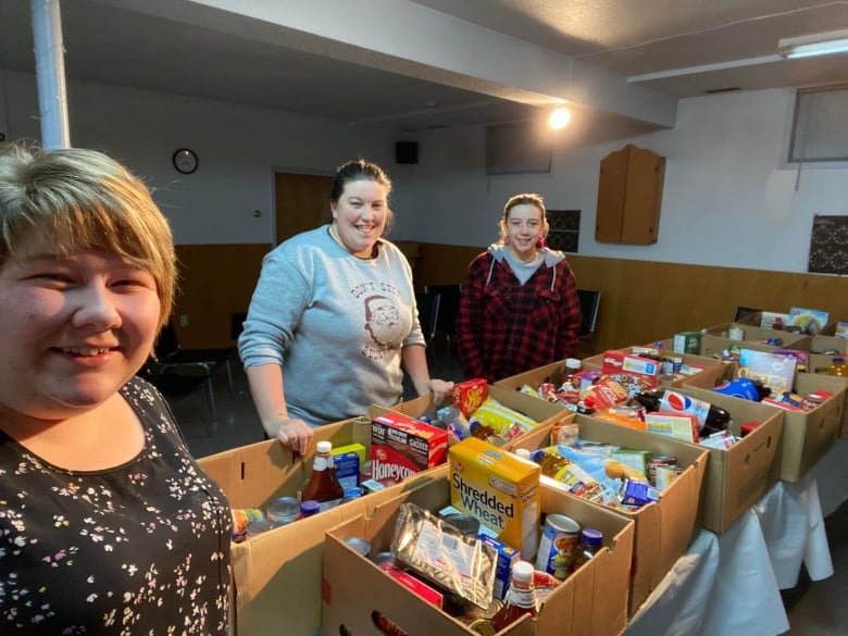 Three volunteers packing up food items into boxes for food hampers for the Salvation Army.