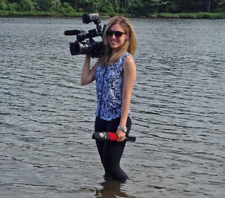 A woman holds a CBC-branded microphone and camera.