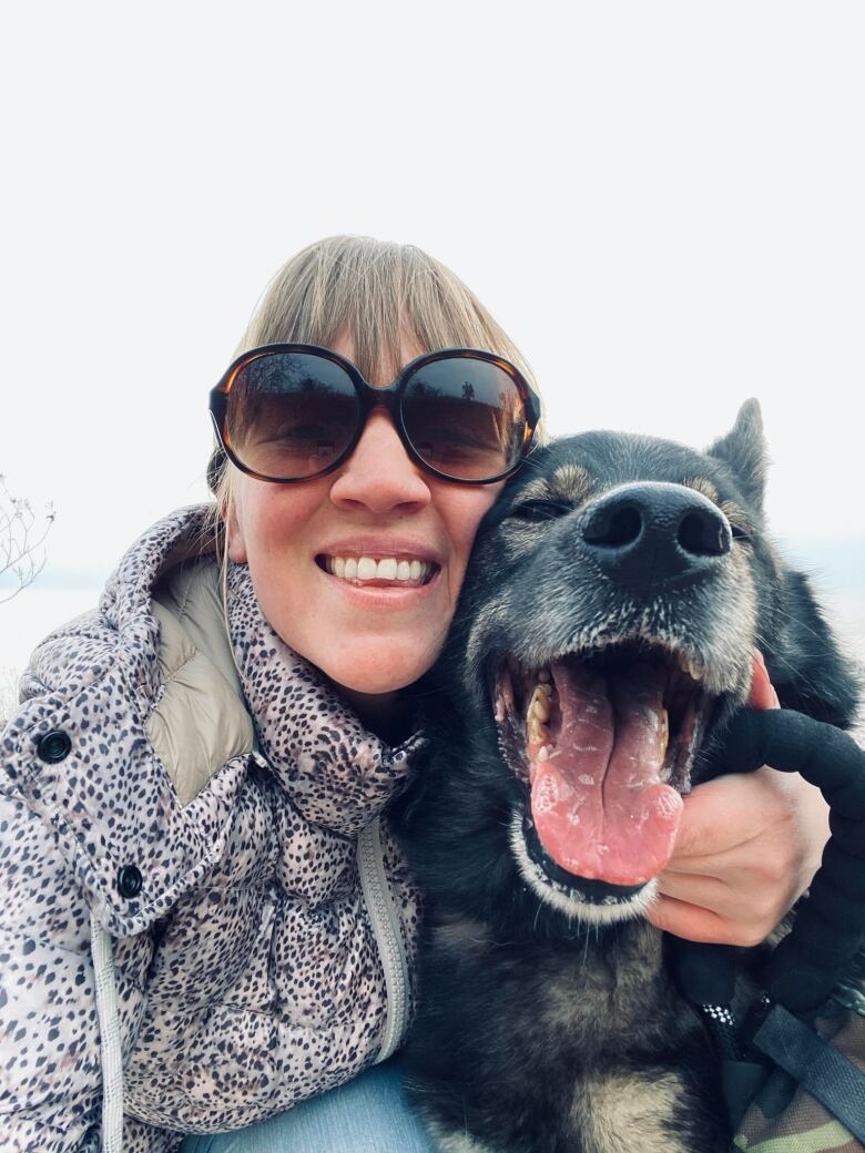 A smiling woman holds her pet dog lovingly.