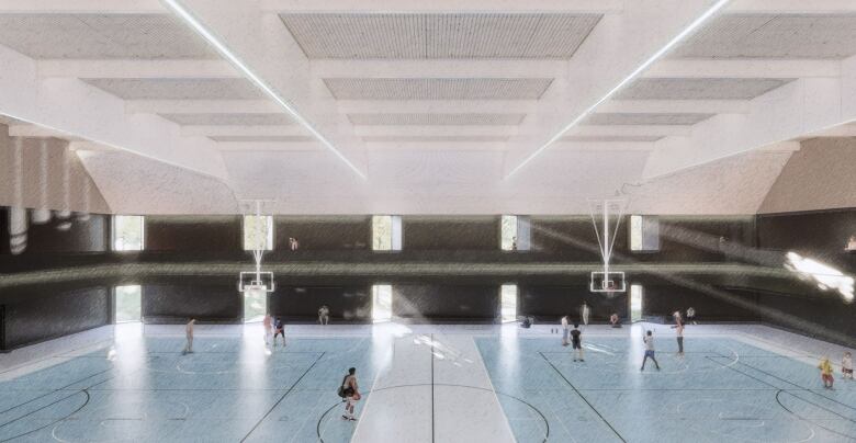 A large room with people playing basketball on two courts with light shining through several windows. 