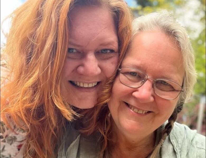 Two women embrace and smile for a photograph.