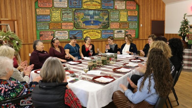 14 women sitting around a table clap.