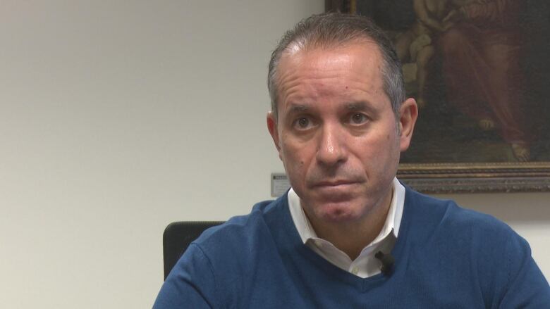 Bill Marra sits in a boardroom with a neutral expression looking to the left side of the camera.