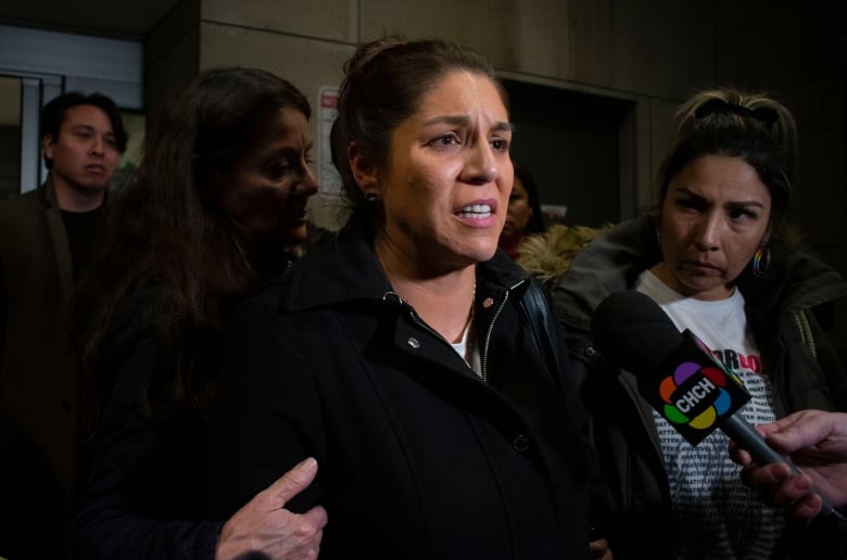 A woman speaks to reporters.