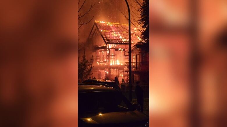 A large duplex home is seen fully ablaze at night.