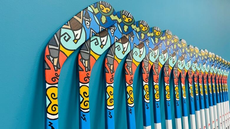 A set of 20 hockey sticks for the International Ice Hockey Federation World Juniors. The corner of hockey blade has a green turtle beside a salmon, eagle and coyote. 