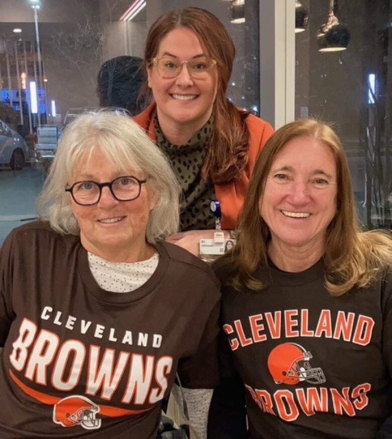 Three woman, including two women wearing Cleveland Browns shirts, look at the camera.