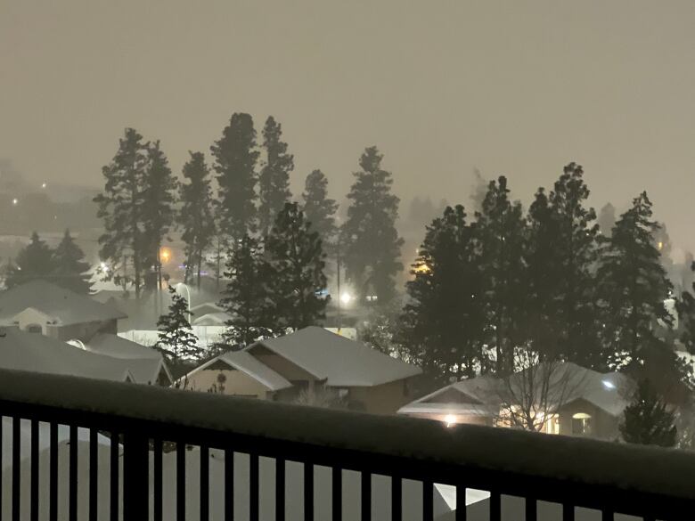 Looking out over a deck at houses, trees covered in snow and the air blanketed in fog