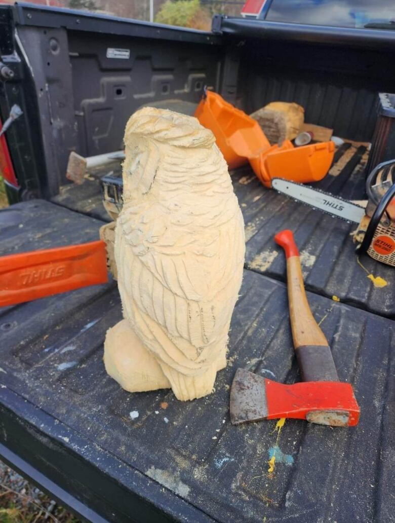 A wooden sculpture of an owl in a truck. 