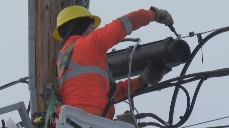 A phone company worker repairing a telephone pole.