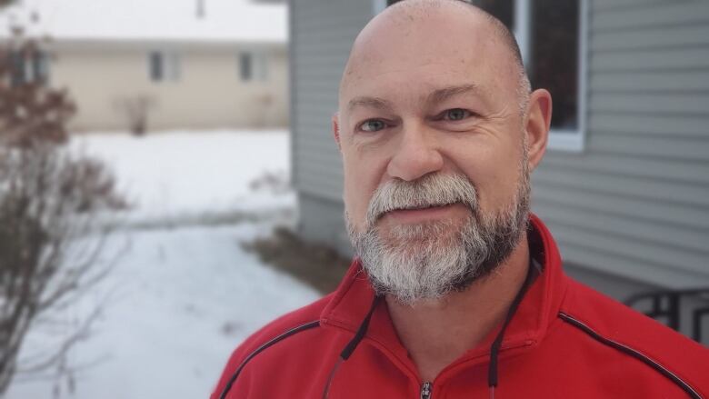 A man with a shaved head and a grey beard.