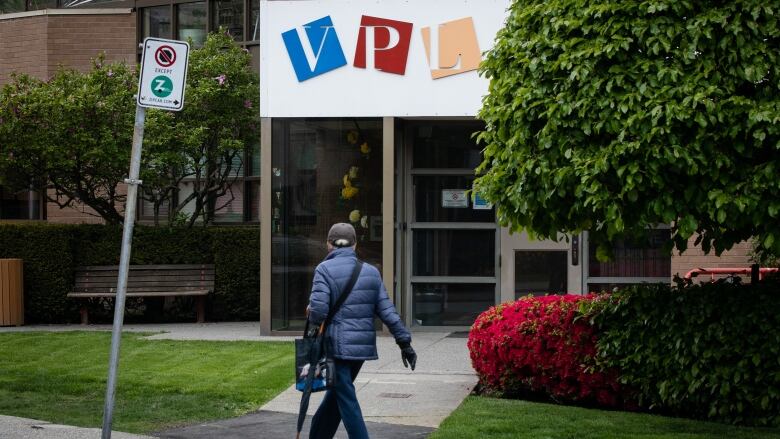 A man walks by a Vancouver Public Library sign.