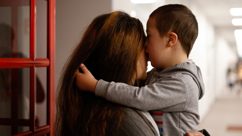 A child hugs a woman with long hair