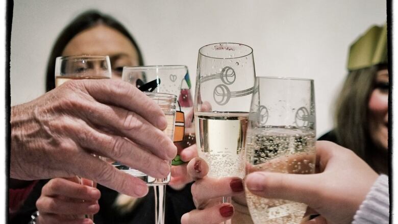 People raise champagne flutes in a toast.