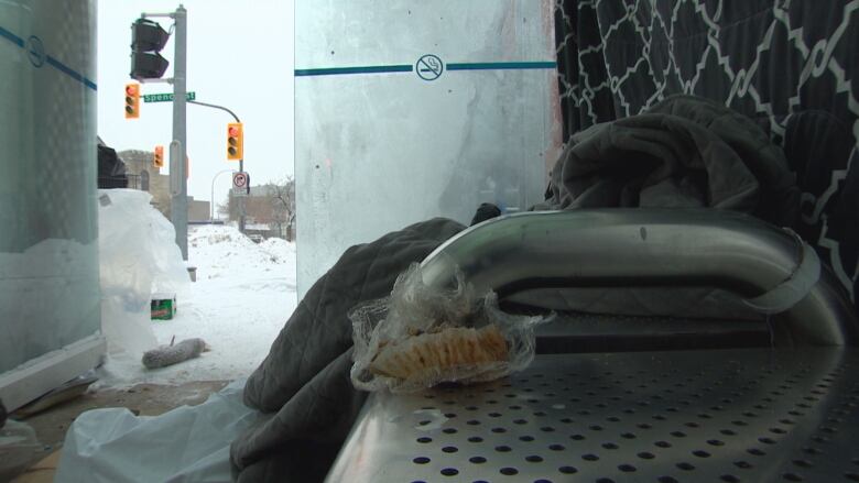 A muffin wrapper and a jacket sit on a bench, with traffic lights in the background.