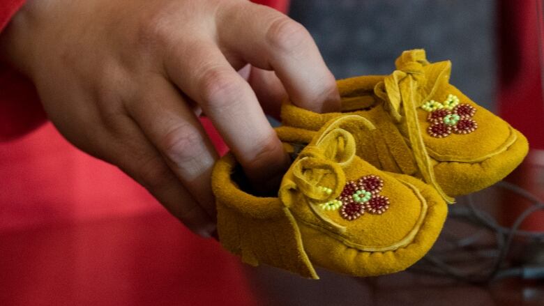 A pair of childrens moccasins represents the tens of thousands of First Nations children who are forcibly removed from their homes, communities and families.