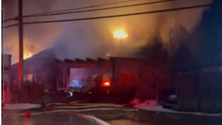 Fire and smoke can be seen coming from the roof of the building housing the restaurant, with safety cones in the foreground.