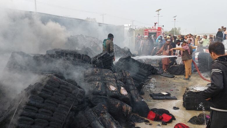 People douse a cargo supply truck after it was hit during the artillery shelling, in the Pakistan-Afghanistan border town of Chaman, Pakistan, December 11, 2022.  Amidst a deteriorating relationship between the two countries, Pakistan has told the Canadian government it will not  deport Afghans bound to this country.  REUTERS/Abdul Khaliq Achakzai     