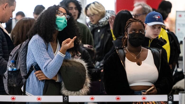 Passengers look up at a sign at the airport.