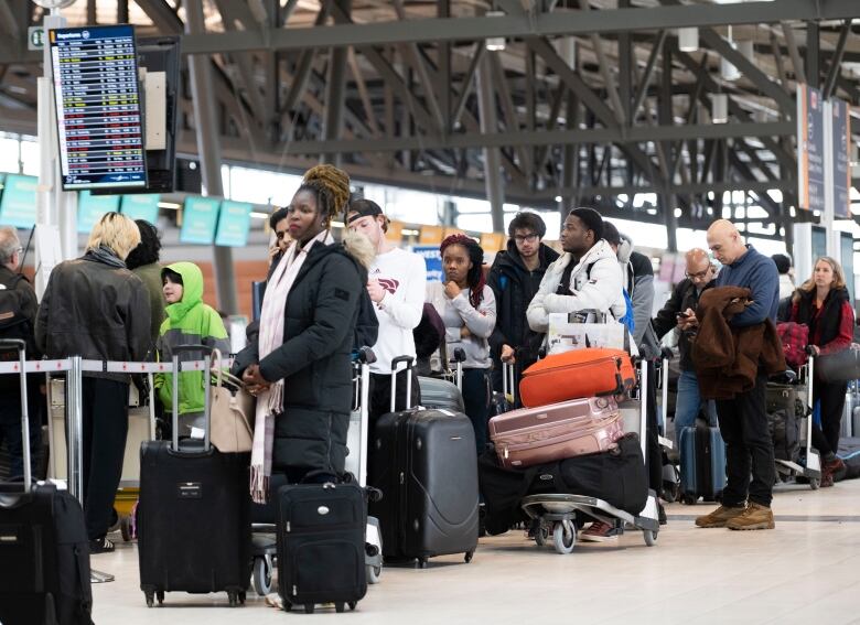 A group of passengers waits in line at the Ottawa International Airport.