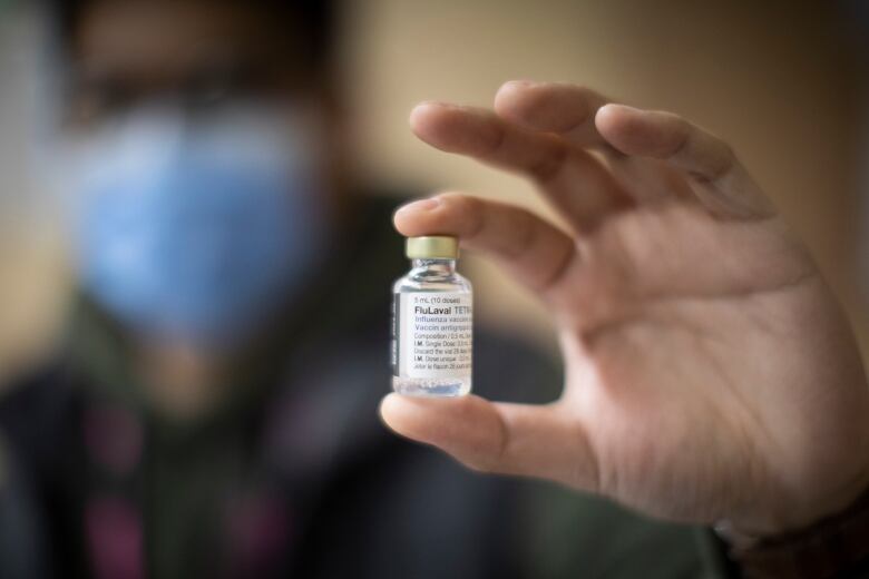 A hand holds a vaccine bottle.