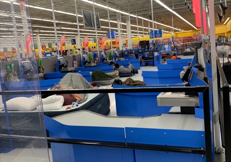 People sleeping on air mattresses in the self check-out area