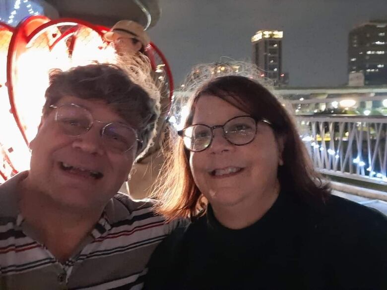 A man and a woman take a smiling photo outdoors at night