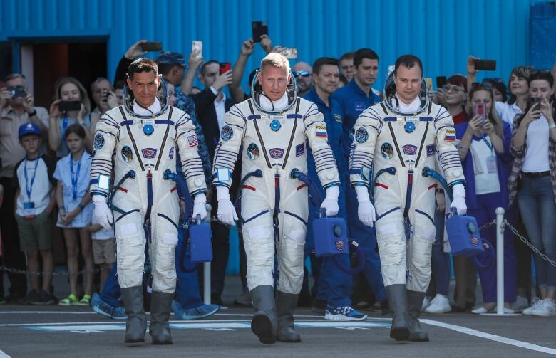 NASA astronaut Frank Rubio and Roscosmos cosmonauts Sergey Prokopyev and Dmitri Petelin walk side by side. 