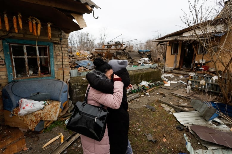 Two people embrace amid the debris of destroyed homes.