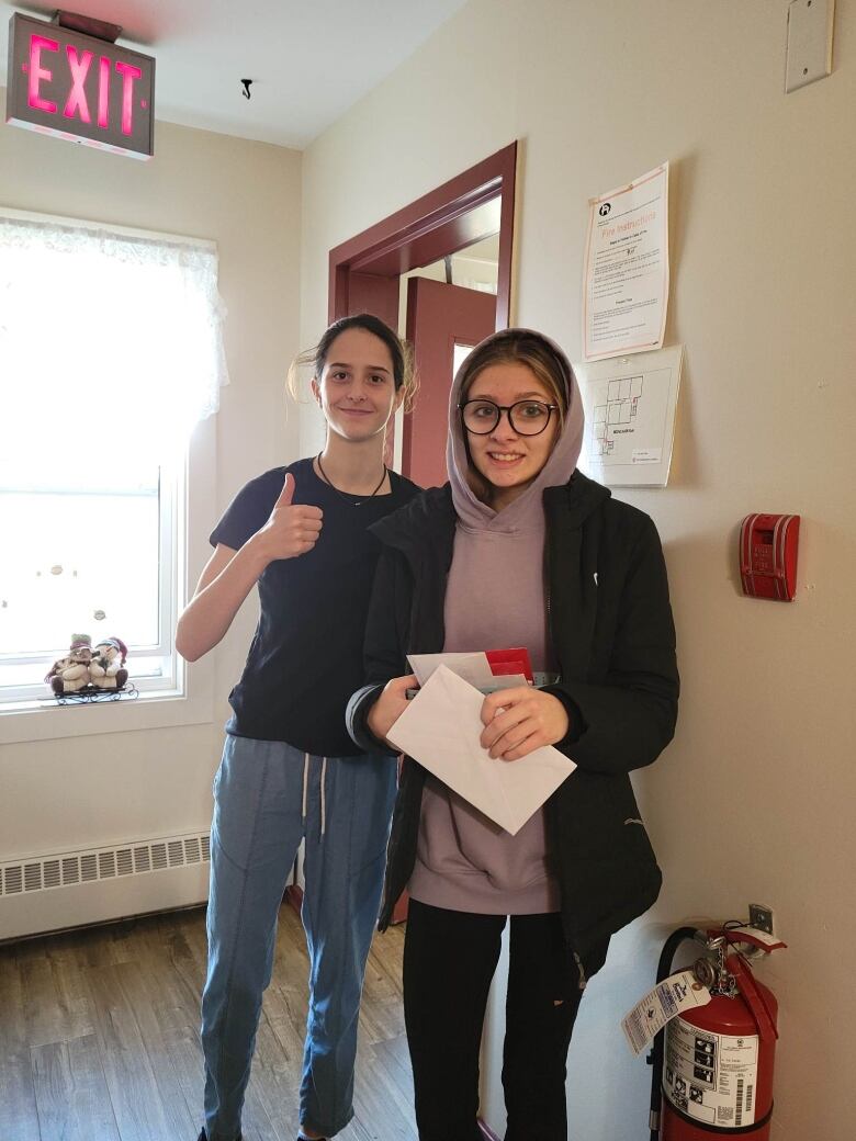 Two girls giving a thumbs up. 