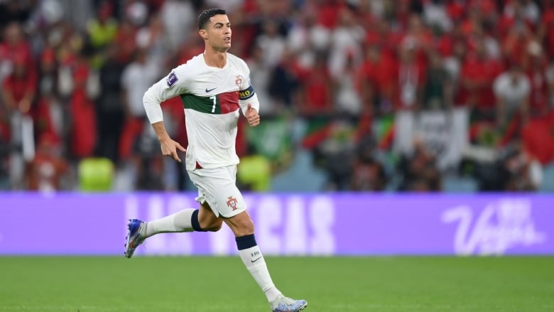 A soccer player from Portugal runs on the field, with no other player in sight.