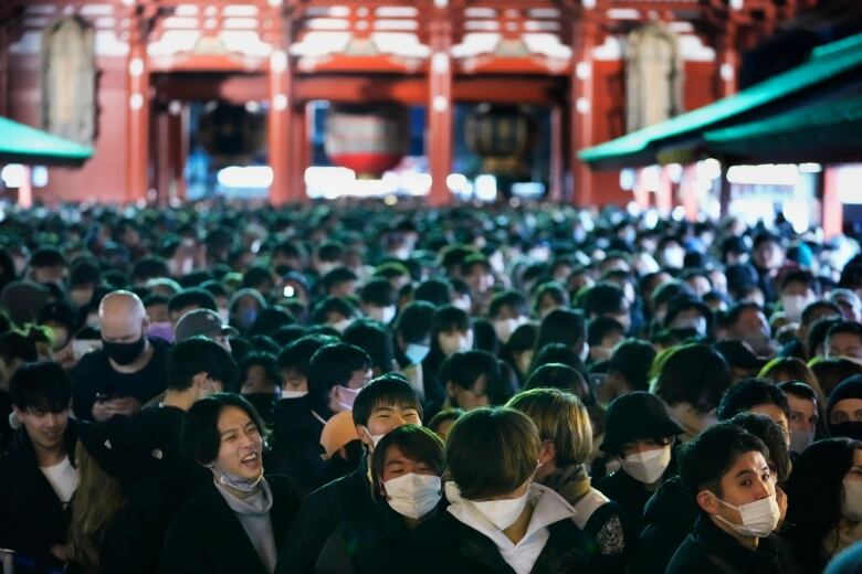 A group of smiling people wait in queue before they pray at the main hall of Sensoji Buddhist temple on New Year's Day in Tokyo