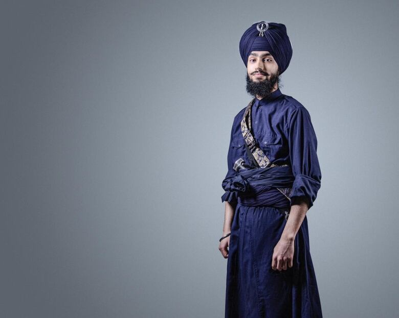 A Sikh man wearing traditional clothes poses for a headshot.