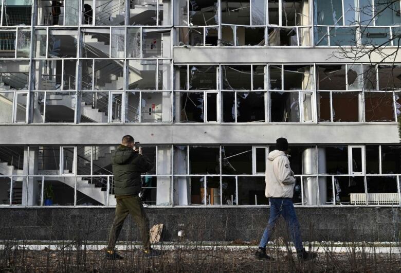 People walk by a damaged school in Kyiv.