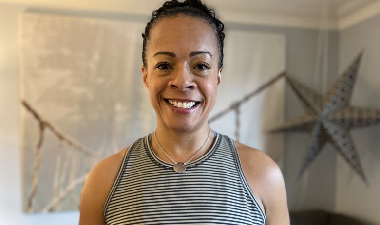 A woman wearing a striped tank top smiles.