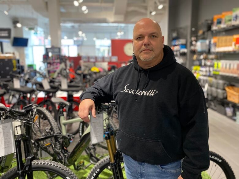 Man stands beside electric bike in a shop