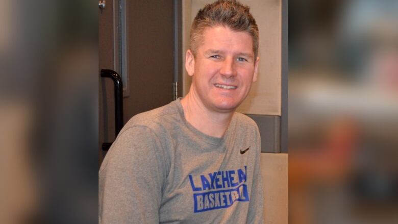 A man wearing a Lakehead basketball shirt looks at the camera.