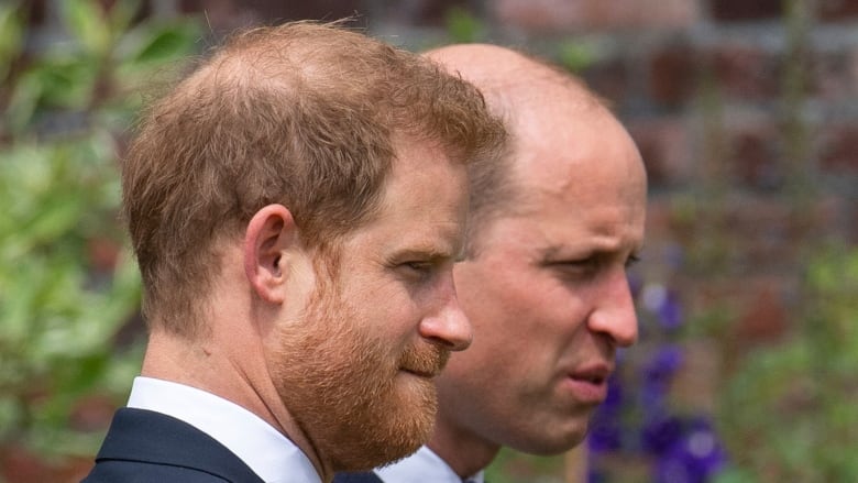 Two men in suits are seen in closeup.