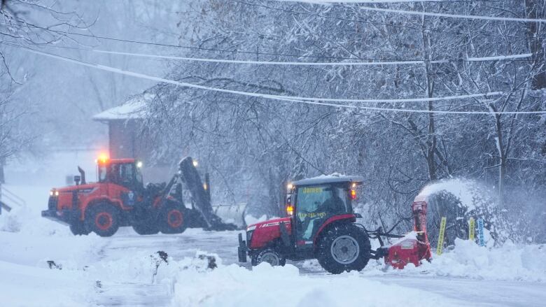 Two pieces of snow-clearing equipment work on a road on a snowy day.