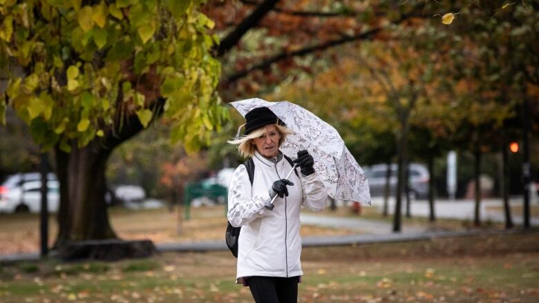 A person with blonde hair and an umbrella is pictured walking in windy weather in downtown Vancouver.