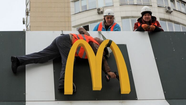 Workers are seen removing the McDonald's logo from a building in Almaty, Kazakhstan.