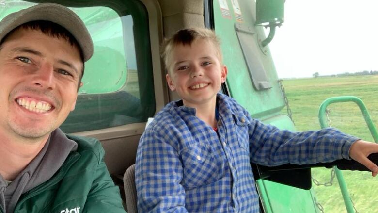 A man and his son drive farm equipment.